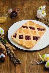 Traditional Polish Easter sweetness Mazurek made of sand dough with two species of jam on a white ceramic dish on a brown wooden background.