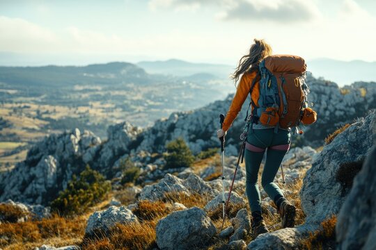 Adventurous young woman climbing a rocky hill with hiking gear in a scenic landscape
