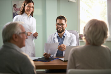 Smiling doctor and female nurse  talking to senior  couple  in hospital