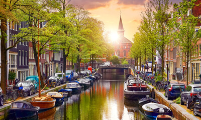 Channel in Amsterdam Netherlands. Old european city with Houses on the river Amstel, famous travel destination Europe. Houseboats parked along channels. Sunset evening
