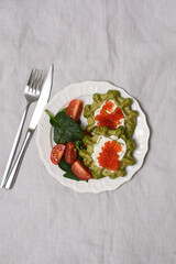Spinach and orange lentils vafles with cottage cheese, caviar garnished with Tomato and Spinach, beautifully presented on white plate. Top view.