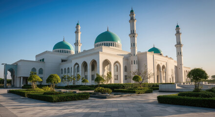 Naklejka premium Stunning white mosque with green domes and minarets surrounded by gardens pathways on sunny day