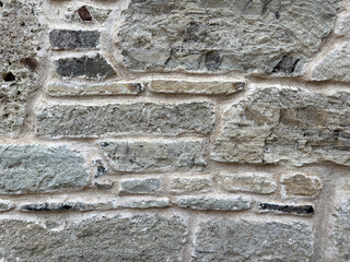 A close-up of a granite stone wall with a rough, grunge surface. The textured cobblestones and aged appearance evoke historic charm, making it ideal for vintage or architectural backgrounds.
