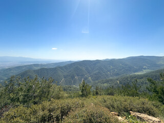 Vast green mountains under a bright blue sky with sunlight casting over the forested landscape background texture