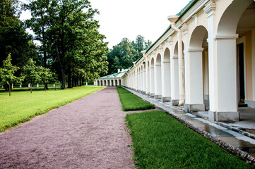 Green city park with walking path, trail next to decorative building, cloudy day