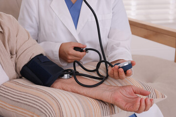 Doctor measuring patient's blood pressure indoors, closeup