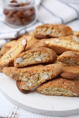 Tasty almond biscuits (Cantuccini) and nuts on white wooden table, closeup