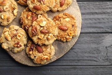 Tasty cookies with nuts on dark wooden table, top view. Space for text