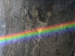 A vibrant rainbow reflection on a dark gray marble floor, showcasing the interplay of light and texture. This close-up captures the colorful gradient and natural patterns in the stone.