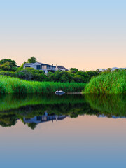 Obraz premium Scenic view of houses along the riverbank with water reflections in Stanford, Western Cape, South Africa