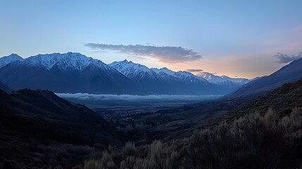 Majestic mountain range under soft twilight hues with misty valleys below