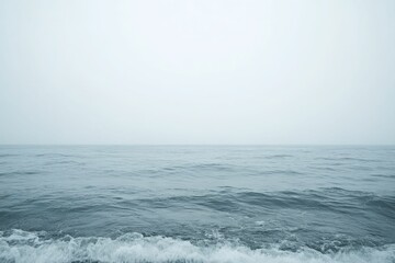 Ocean waves crash on foggy shore.