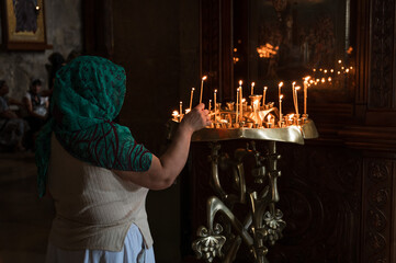 a woman lights a candle in front of a holy image in an Orthodox church in Svetitskhoveli Cathedral...