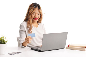 Asian woman using a credit card in front of a laptop computer