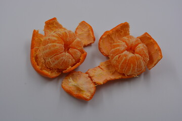 Healthy, wholesome food, fruits. 
Small slices of orange tangerine are located on a white matte background. Two not whole orange tangerines.