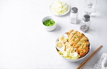 Ramen noodles with meat schnitzel slices, peking cabbage, eggs and scallions in a bowl