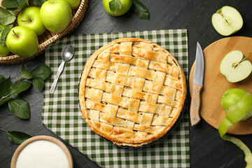 Flat lay composition with tasty homemade apple pie and ingredients on dark textured table