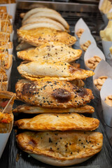 Traditional Spanish and Latin American pies empanadas with different fillings, at farmer's market in bakery with tuna fish, sweet onion, goat cheese, bacon