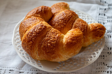 Fresh baked two buttered croissants served in restaurant for continental or French breakfast close up