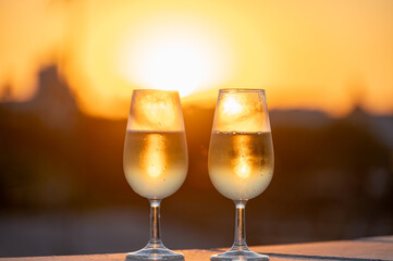 Drinking of cava or champagne sparkling wine on outdoor roof terrace with view on central part of old Sevilla, Andalusia, Spain sunset