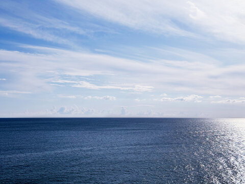 Shiny blue sea and white clouds in sky horizon.