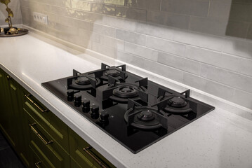 Black glass gas stove cooker on stone countertop