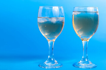 Close-Up of Two Glasses of White Wine with Ice on a Vibrant Blue Background, Copy Space for Your Text