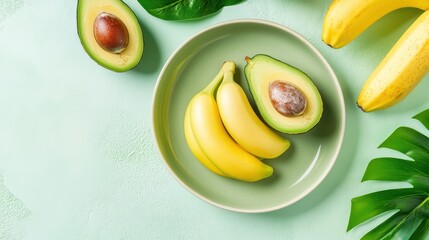 Fresh avocados and bananas arranged on a green plate with tropical leaves, celebrating National Avocado and Banana Month.