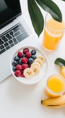 Breakfast at the workplace, yogurt with berries and appelsin juice, laptop in the background