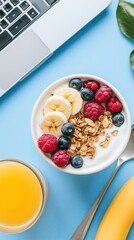 Breakfast at the workplace, yogurt with berries and appelsin juice, laptop in the background