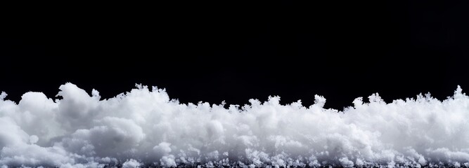 A snowdrift on a black background, creating contrast and a feeling of winter emptiness. The snow looks soft and airy, with many small snowflakes forming characteristic waves