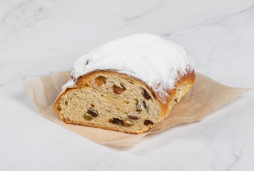 German Christmas cake with of spices, raisins, candied fruits, and almond cream. Stollen. Sprinkled with powdered sugar. Close up