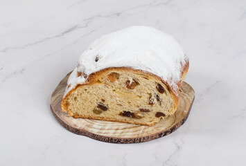 Stollen. Traditional German Christmas yeast cake with lots of spices, raisins, candied fruits, and almond cream. Sprinkled with powdered sugar. On a wooden board. White background