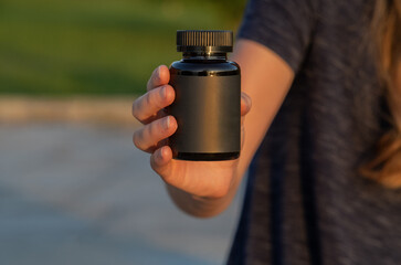 Minimalist black bottle with blank label with hand holding outside for wellness concept
