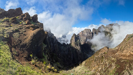 A breathtaking trail of Pico do Arieiro, Madeira, Portugal. Steep volcanic cliffs, dense mist, and vivid blue skies create a dramatic and adventurous mountain landscape perfect for exploration.