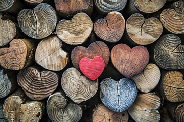 Pile of wooden hearts with a red heart in the middle. The red heart is surrounded by other hearts, creating a sense of unity and love