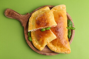 Tasty vegetarian calzones with tomato, cheese and basil on green background, top view