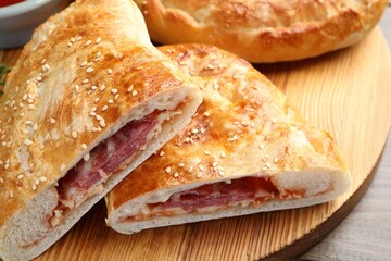 Pieces of calzone pizza served on wooden table, closeup