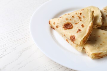 Delicious folded crepes on white wooden table, closeup. Space for text