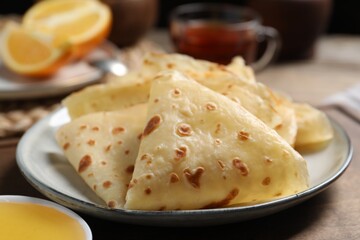 Delicious crepes and honey on wooden table, closeup