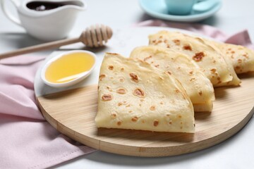Delicious crepes and honey on light table, closeup