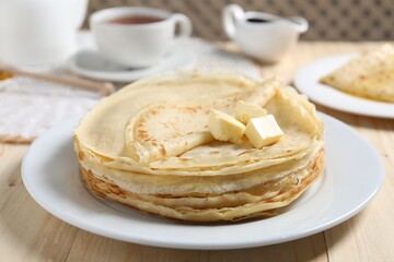 Stack of tasty crepes with butter on wooden table, closeup