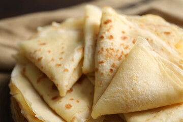Tasty thin crepes on blurred background, closeup