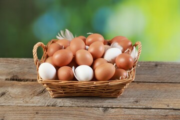 Many raw eggs in basket on wooden table, closeup
