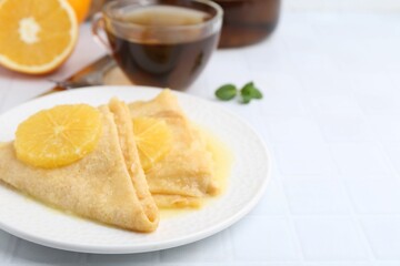 Delicious Crepes Suzette served on white tiled table, closeup. Space for text