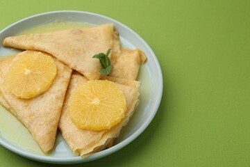 Delicious Crepes Suzette on green background, closeup