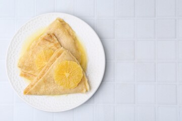 Delicious Crepes Suzette on white tiled table, top view. Space for text