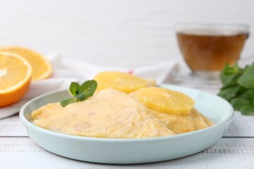 Delicious Crepes Suzette, mint, tea and oranges on white wooden table, closeup
