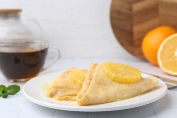 Delicious Crepes Suzette served on white tiled table, closeup