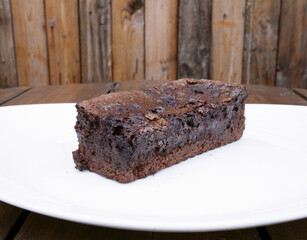 Sweet desserts. Closeup view of a slice of chocolate and strawberries cake with a rustic wooden background